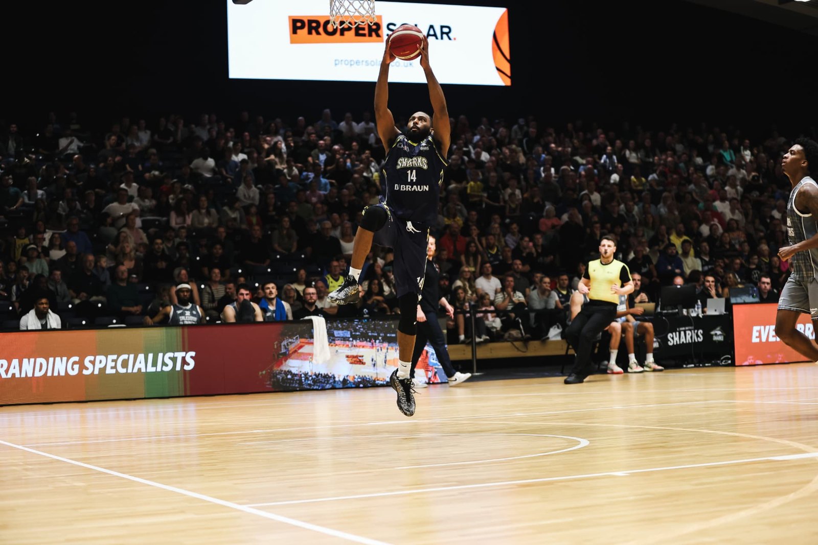 Maceo Jack of the Sheffield Sharks rising for a dunk, with Proper Solar advertising boards behind him