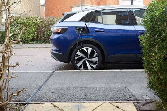 Electric car charging at the kerb with the cable running across the pavement inside a flush channel