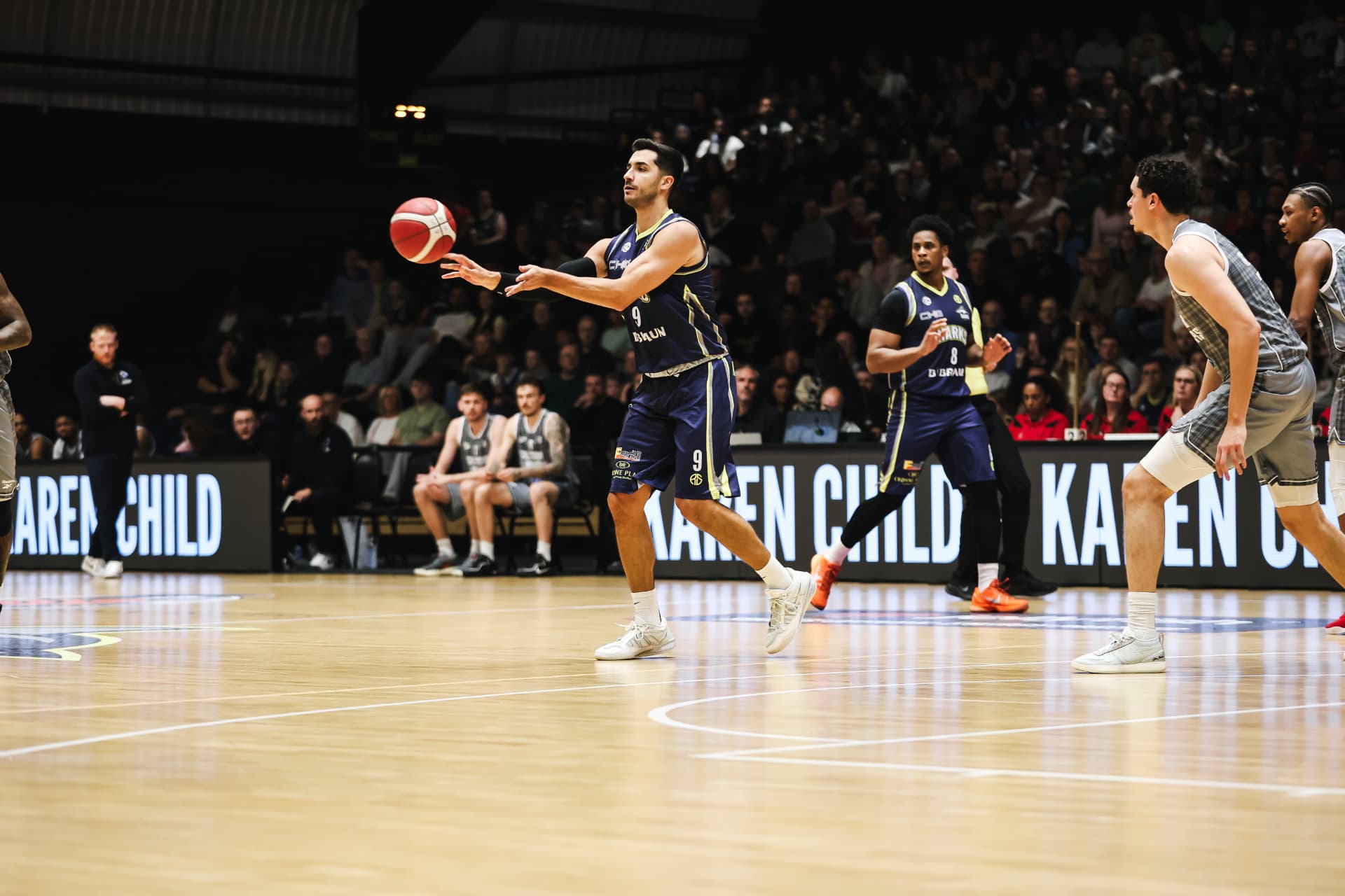 Jordan Ratinho throwing a pass for the Sheffield Sharks, with Proper Solar advertising behind him